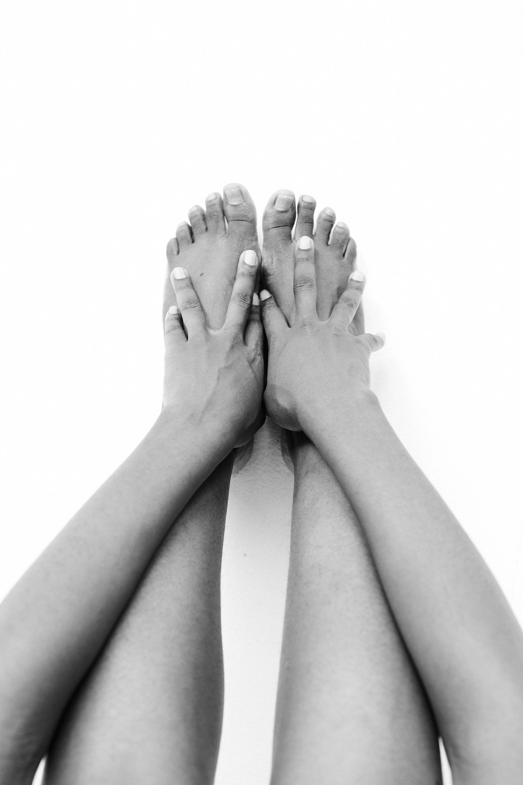 Artistic black and white photo focusing on hands and feet for a minimalist aesthetic.
