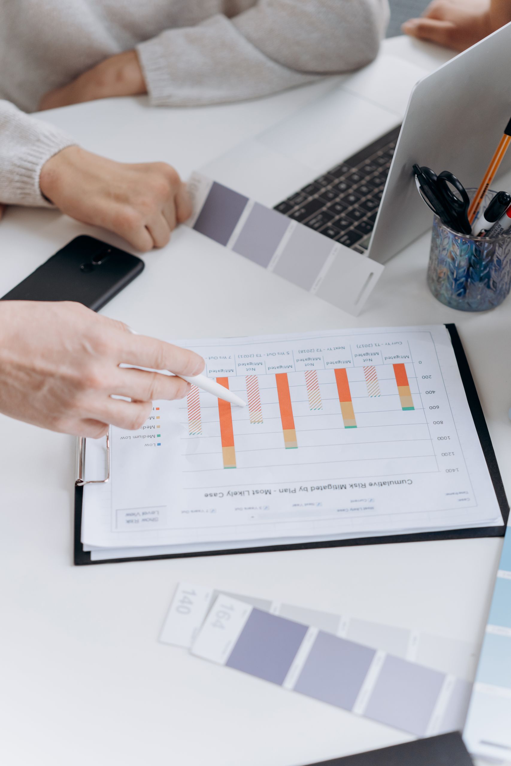 Hands pointing at performance charts during a business meeting.